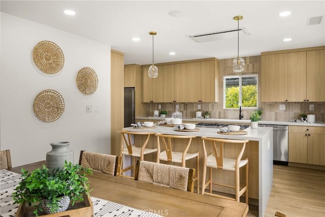5161 E 27th St, Long Beach, CA 90815 - kitchen with stainless steel appliances, light countertops, light brown cabinetry, tasteful backsplash, and a kitchen breakfast bar