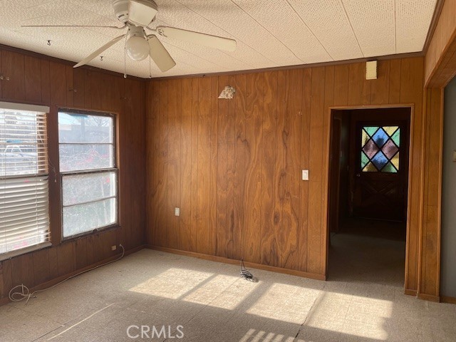 100 Aliso St, Needles, CA 92363 - unfurnished room with wood walls, a ceiling fan, and baseboards