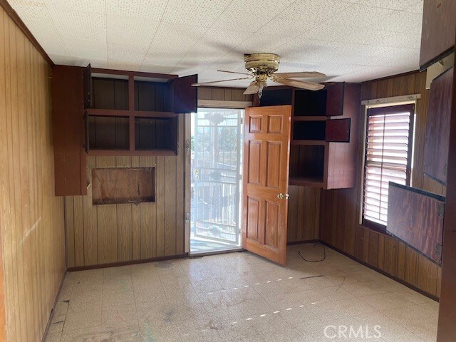 100 Aliso St, Needles, CA 92363 - empty room with wooden walls, light floors, ceiling fan, and baseboards