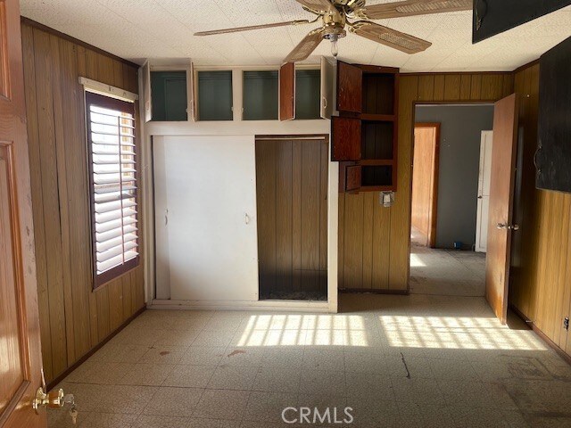 100 Aliso St, Needles, CA 92363 - unfurnished bedroom with wooden walls, tile patterned floors, and baseboards
