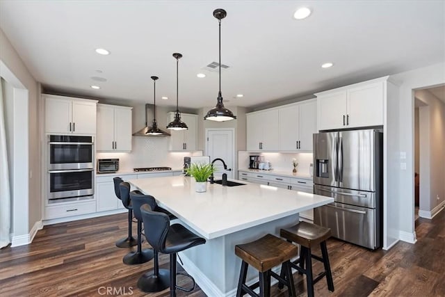 11313 Atlas Ct, Corona, CA 92883 - kitchen featuring appliances with stainless steel finishes, wall chimney range hood, tasteful backsplash, recessed lighting, and white cabinets