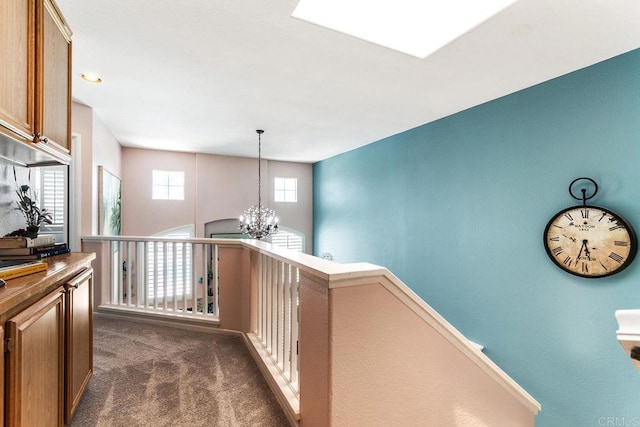 4610 Los Alamos Way Unit C, Oceanside, CA 92057 - hall with an upstairs landing, dark carpet, and a chandelier