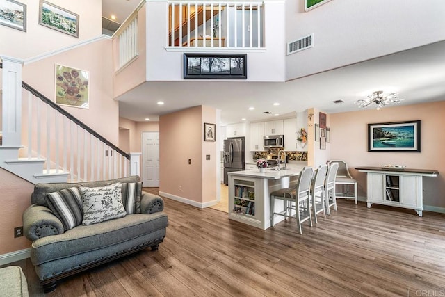 4610 Los Alamos Way Unit C, Oceanside, CA 92057 - living room featuring a towering ceiling, stairway, wood finished floors, baseboards, and recessed lighting
