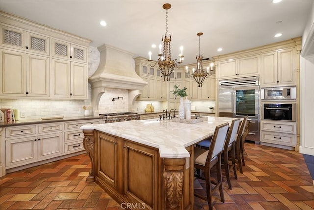 755 Carriage House Dr, Arcadia, CA 91006 - kitchen featuring cream cabinetry, built in appliances, a chandelier, brick flooring, and recessed lighting