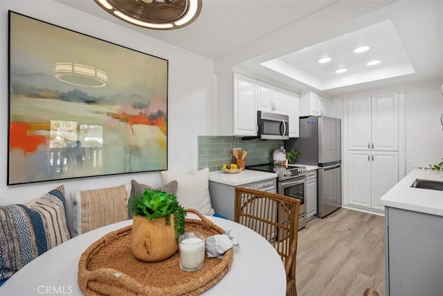 25611 Quail Run Unit 18, Dana Point, CA 92629 - kitchen with appliances with stainless steel finishes, light wood finished floors, light countertops, a tray ceiling, and tasteful backsplash