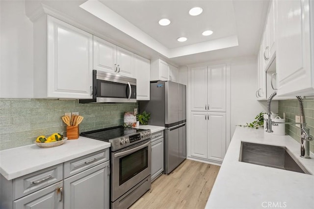 25611 Quail Run Unit 18, Dana Point, CA 92629 - kitchen featuring appliances with stainless steel finishes, a tray ceiling, light countertops, white cabinetry, and recessed lighting