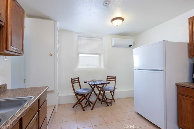 1615 Halsey St, Redlands, CA 92373 - kitchen with freestanding refrigerator, an AC wall unit, brown cabinetry, light tile patterned flooring, and dark countertops