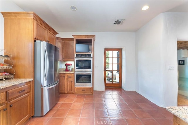 1615 Halsey St, Redlands, CA 92373 - kitchen with appliances with stainless steel finishes, brown cabinetry, light stone countertops, light tile patterned floors, and recessed lighting