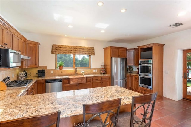 1615 Halsey St, Redlands, CA 92373 - kitchen featuring appliances with stainless steel finishes, a peninsula, brown cabinets, recessed lighting, and tasteful backsplash