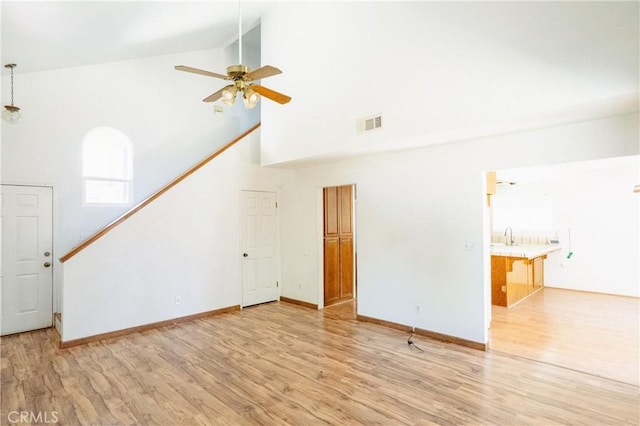 3117 Andre Ln, Turlock, CA 95382 - unfurnished living room with high vaulted ceiling, light wood finished floors, ceiling fan, and stairway