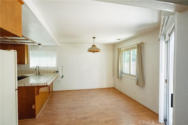 3117 Andre Ln, Turlock, CA 95382 - kitchen featuring tile counters, light wood-style flooring, plenty of natural light, and brown cabinetry