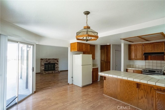 3117 Andre Ln, Turlock, CA 95382 - kitchen with freestanding refrigerator, under cabinet range hood, brown cabinets, and tile counters