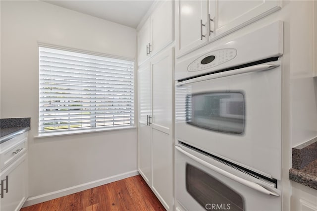 15403 Domart Ave, Norwalk, CA 90650 - kitchen featuring dark wood finished floors, white double oven, dark countertops, white cabinets, and baseboards