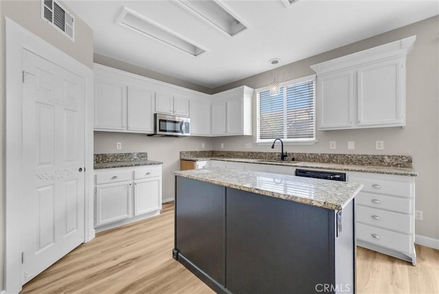 46186 Via Ln, Tranquila, Temecula, CA 92592 - kitchen with stainless steel microwave, light wood finished floors, and white cabinets