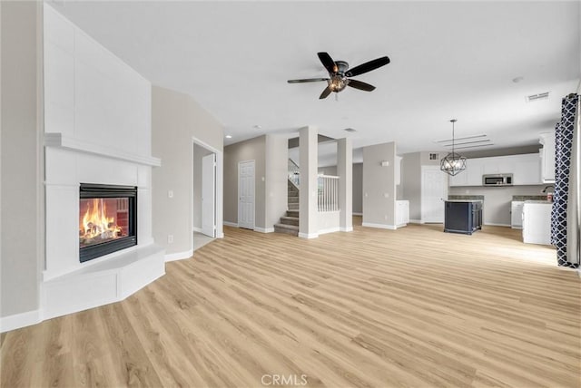 46186 Via Ln, Tranquila, Temecula, CA 92592 - unfurnished living room featuring light wood-type flooring, a glass covered fireplace, a ceiling fan, and stairway