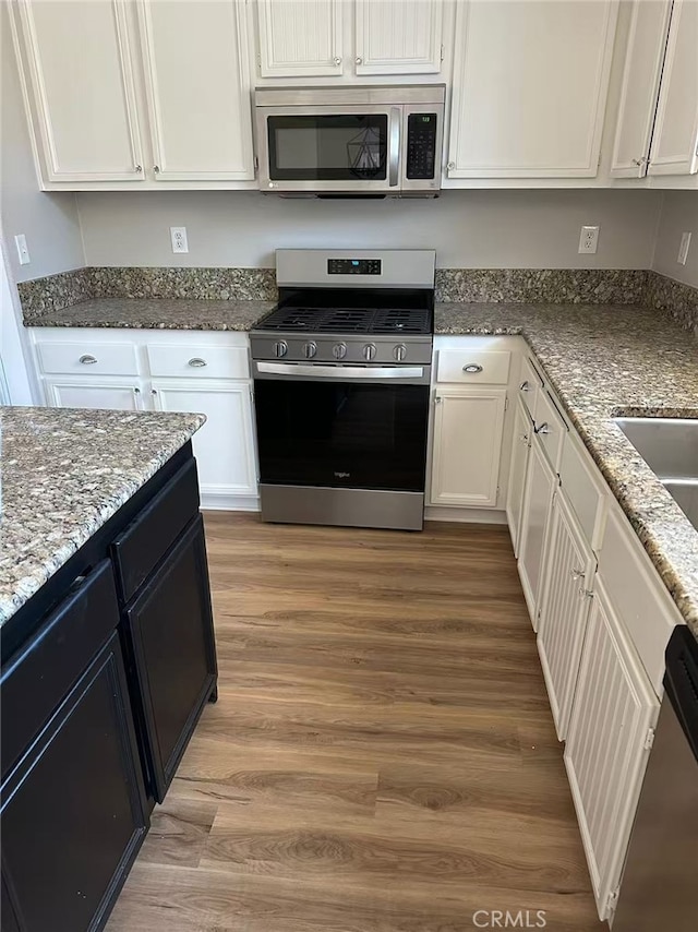 46186 Via Ln, Tranquila, Temecula, CA 92592 - kitchen featuring stainless steel appliances, white cabinetry, stone counters, and light wood-type flooring