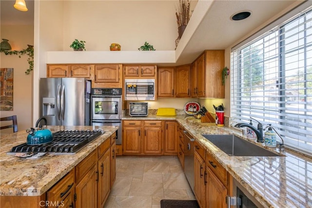 31436 Corte Sonora, Temecula, CA 92592 - kitchen featuring stainless steel appliances, brown cabinets, light stone counters, light stone finish floors, and a high ceiling