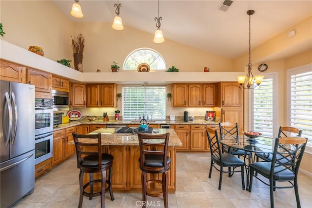 31436 Corte Sonora, Temecula, CA 92592 - kitchen with appliances with stainless steel finishes, brown cabinetry, light stone counters, pendant lighting, and high vaulted ceiling
