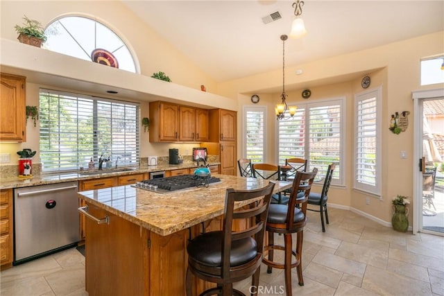 31436 Corte Sonora, Temecula, CA 92592 - kitchen with appliances with stainless steel finishes, a center island, light stone counters, brown cabinetry, and stone tile flooring