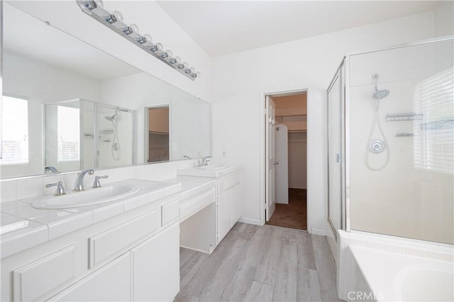31460 Tulette Ln, Winchester, CA 92596 - bathroom featuring a stall shower, a walk in closet, wood finished floors, double vanity, and a bath
