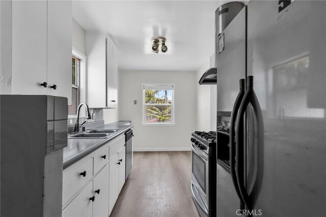 14403 S White Ave, Compton, CA 90221 - kitchen with stainless steel appliances, a sink, white cabinetry, and wood finished floors