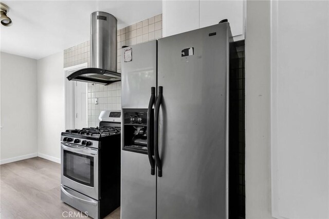 14403 S White Ave, Compton, CA 90221 - kitchen with appliances with stainless steel finishes, island range hood, light wood-type flooring, backsplash, and baseboards