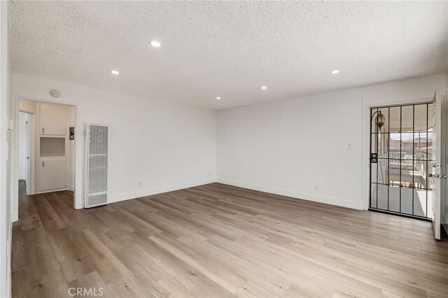 11726 Freeman Ave Unit A, Hawthorne, CA 90250 - empty room with a heating unit, a textured ceiling, light wood finished floors, recessed lighting, and baseboards
