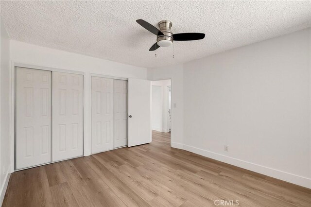 11726 Freeman Ave Unit A, Hawthorne, CA 90250 - unfurnished bedroom featuring two closets, light wood-type flooring, baseboards, a textured ceiling, and ceiling fan