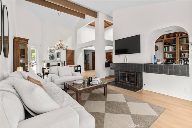 24232 Porto Nuovo, Dana Point, CA 92629 - living room featuring a chandelier, arched walkways, wood finished floors, beam ceiling, and a tile fireplace