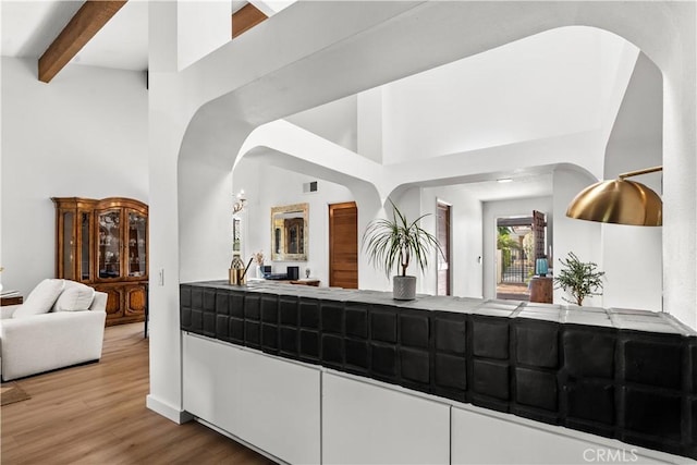 24232 Porto Nuovo, Dana Point, CA 92629 - kitchen with arched walkways, open floor plan, a high ceiling, wood finished floors, and tile counters