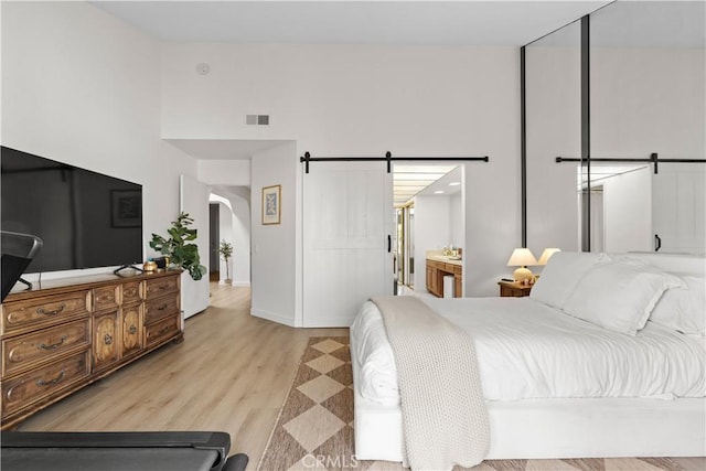 24232 Porto Nuovo, Dana Point, CA 92629 - bedroom with arched walkways, light wood-style flooring, a barn door, baseboards, and a high ceiling