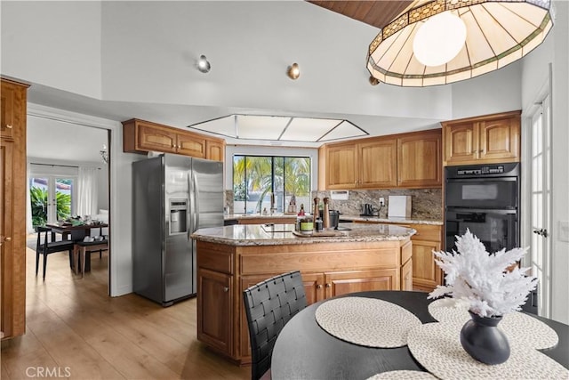 24232 Porto Nuovo, Dana Point, CA 92629 - kitchen featuring stainless steel fridge with ice dispenser, a kitchen island, light wood finished floors, tasteful backsplash, and light stone counters