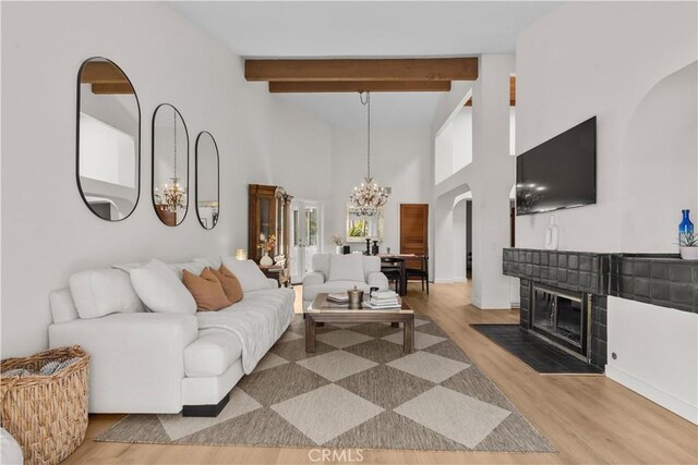 24232 Porto Nuovo, Dana Point, CA 92629 - living area with a chandelier, a fireplace with flush hearth, light wood-style floors, arched walkways, and a high ceiling