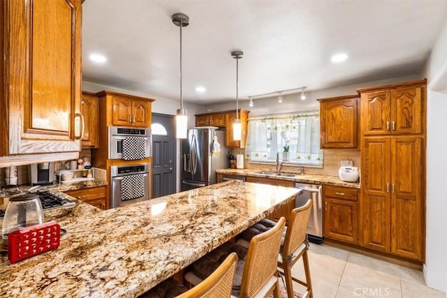 19921 Rambling Rd, Covina, CA 91724 - kitchen featuring stainless steel appliances, a sink, brown cabinets, a peninsula, and light stone counters