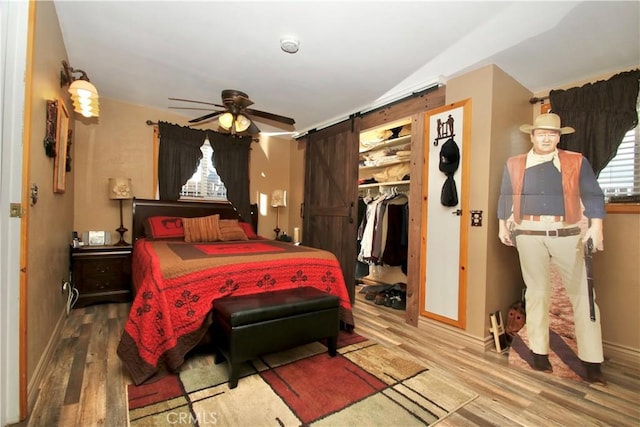 1910 Artesia Ave, Landers, CA 92285 - bedroom featuring wood finished floors, a barn door, a walk in closet, and ceiling fan