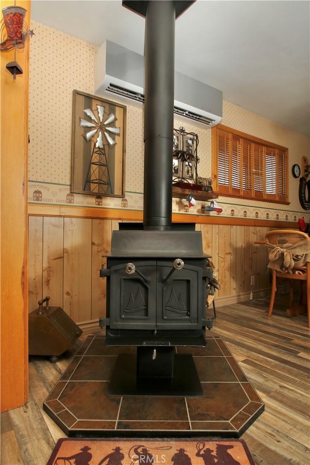 1910 Artesia Ave, Landers, CA 92285 - detailed view of wallpapered walls, a wood stove, wood finished floors, wood walls, and a wainscoted wall