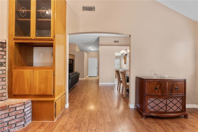 1214 Mallorca St, Upland, CA 91784 - hall featuring arched walkways, light wood-style floors, a chandelier, baseboards, and lofted ceiling