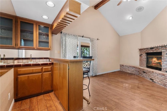 1214 Mallorca St, Upland, CA 91784 - kitchen with a sink, light wood-style flooring, a peninsula, a breakfast bar area, and brown cabinets