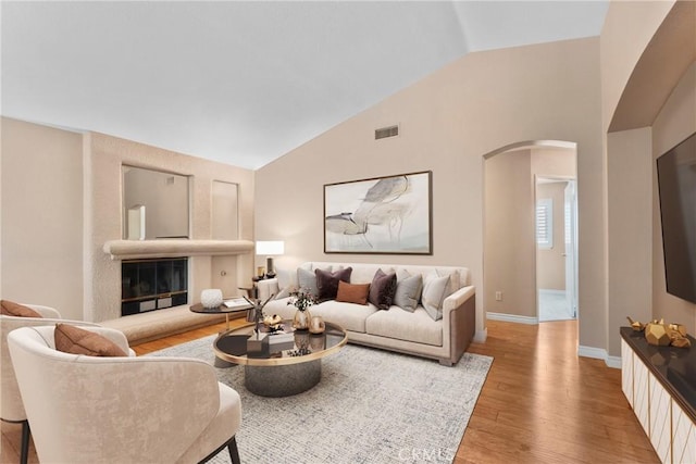 1214 Mallorca St, Upland, CA 91784 - living room with arched walkways, lofted ceiling, wood finished floors, baseboards, and a glass covered fireplace