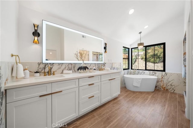 22011 La Puente Rd, Walnut, CA 91789 - bathroom with double vanity, wood finished floors, a freestanding tub, tile walls, and vaulted ceiling