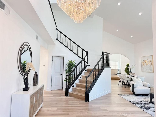 22011 La Puente Rd, Walnut, CA 91789 - stairs featuring a high ceiling, arched walkways, a chandelier, wood finished floors, and recessed lighting