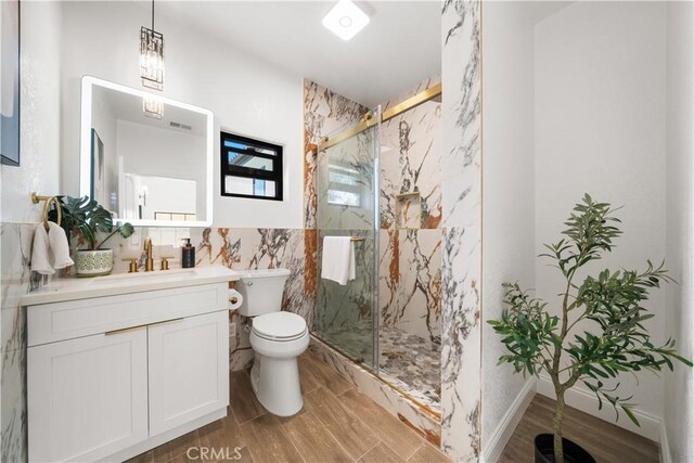 22011 La Puente Rd, Walnut, CA 91789 - bathroom featuring tile walls, toilet, vanity, a marble finish shower, and wood finished floors