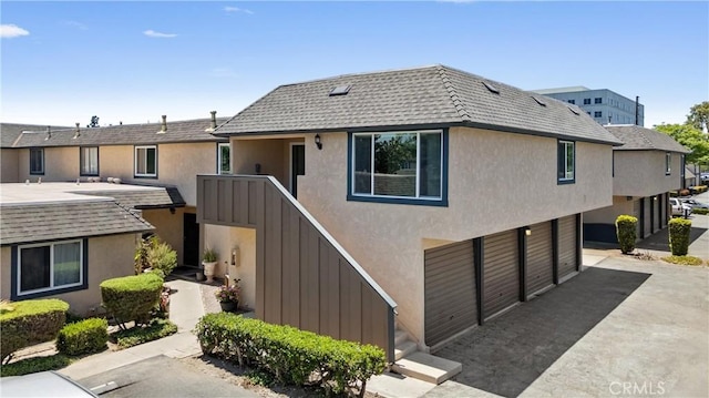 1121 S Dover Cir Unit C44K, Anaheim, CA 92805 - view of front facade with stucco siding, an attached garage, mansard roof, and driveway