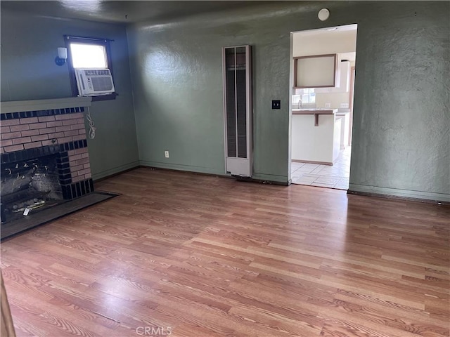1903 E 59th St, Long Beach, CA 90805 - unfurnished living room with wood finished floors, a brick fireplace, a textured wall, baseboards, and cooling unit