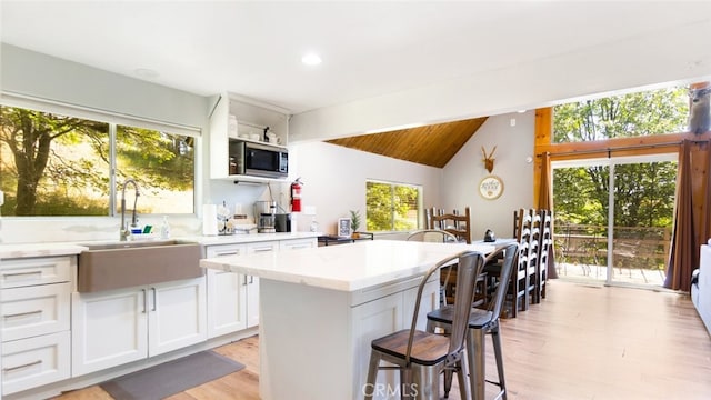 27638 St Bernard Ln, Lake Arrowhead, CA 92352 - kitchen with healthy amount of natural light, white cabinetry, a breakfast bar, vaulted ceiling, and a kitchen island