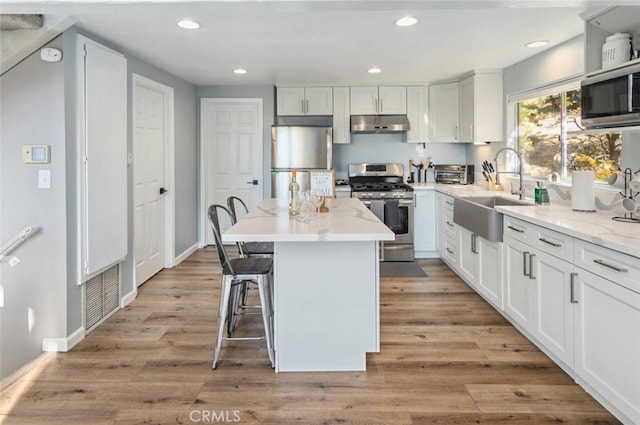 27638 St Bernard Ln, Lake Arrowhead, CA 92352 - kitchen featuring appliances with stainless steel finishes, under cabinet range hood, a kitchen island, white cabinets, and recessed lighting