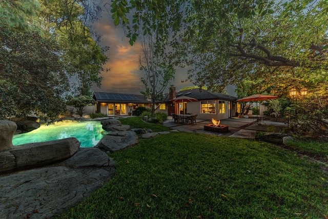 18269 Laurel View Dr, Yorba Linda, CA 92886 - back of property at dusk with an outdoor fire pit, a patio area, roof mounted solar panels, a yard, and an outdoor pool