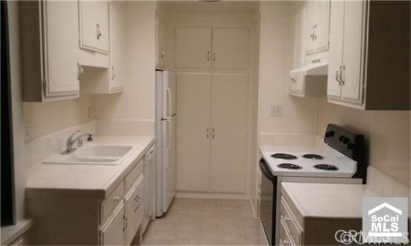 2119 Via Puerta Unit Q, Laguna Woods, CA 92637 - kitchen featuring white appliances, light countertops, ventilation hood, and light tile patterned floors