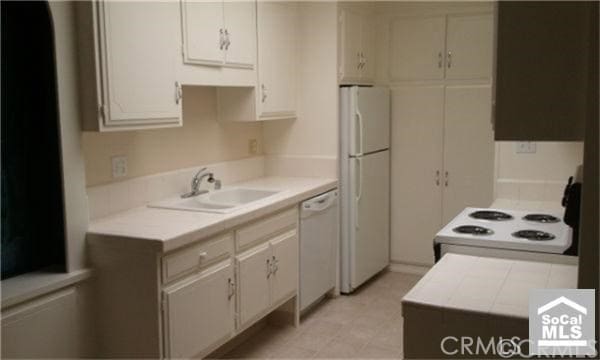 2119 Via Puerta Unit Q, Laguna Woods, CA 92637 - kitchen with white appliances, a sink, and white cabinets
