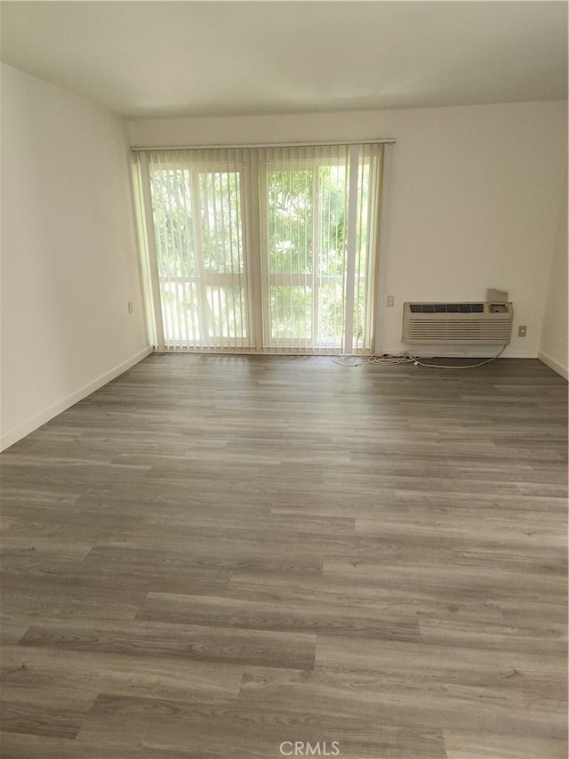 2119 Via Puerta Unit Q, Laguna Woods, CA 92637 - unfurnished room featuring healthy amount of natural light, a wall mounted AC, and wood finished floors